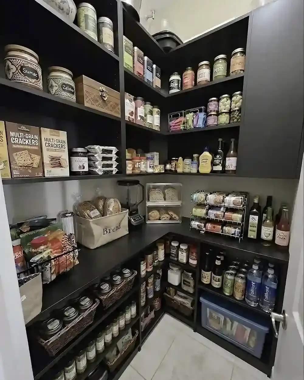 A dark walk-in pantry lined with shelves of jars, baskets and tinned goods