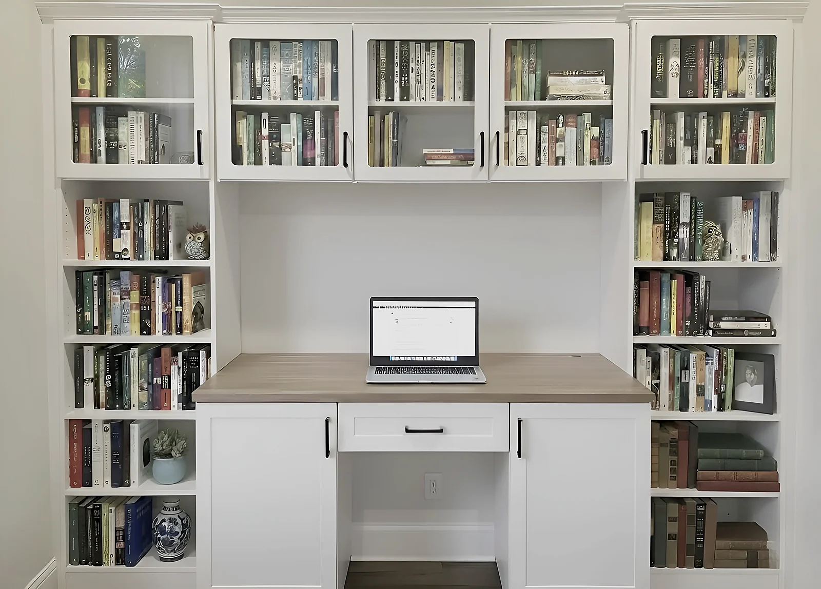 The same home office seen whole — a built-in desk, drawers under the work surface and shelving carried up the wall above it
