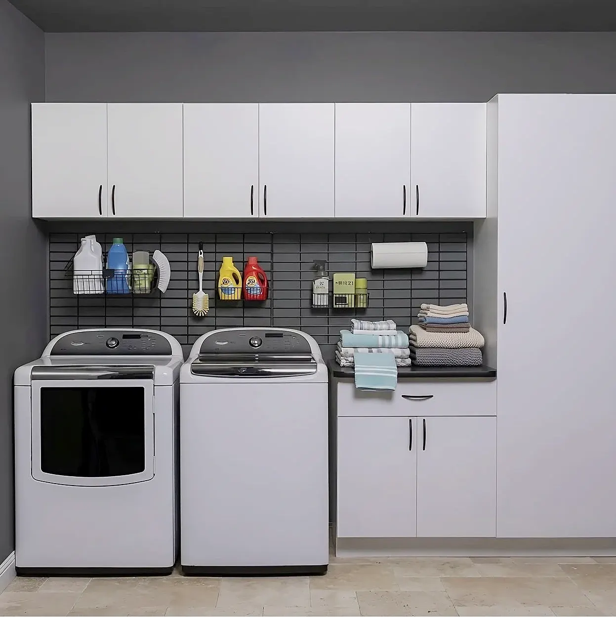 The same laundry room seen whole — upper cabinets for detergent, a folding surface across the machines and storage to one side