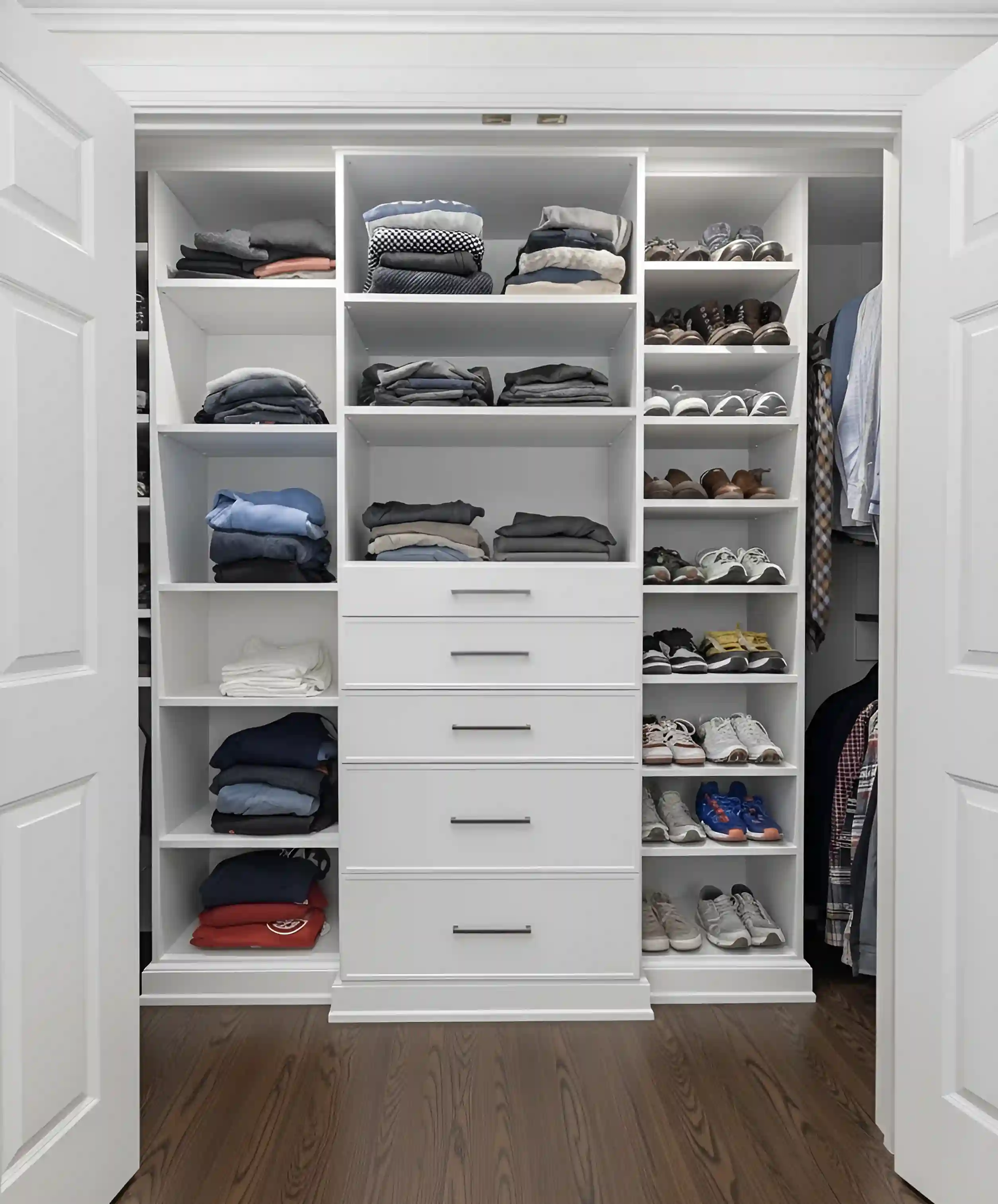 Reach-in closet with hanging rails above and angled shoe shelving along the base